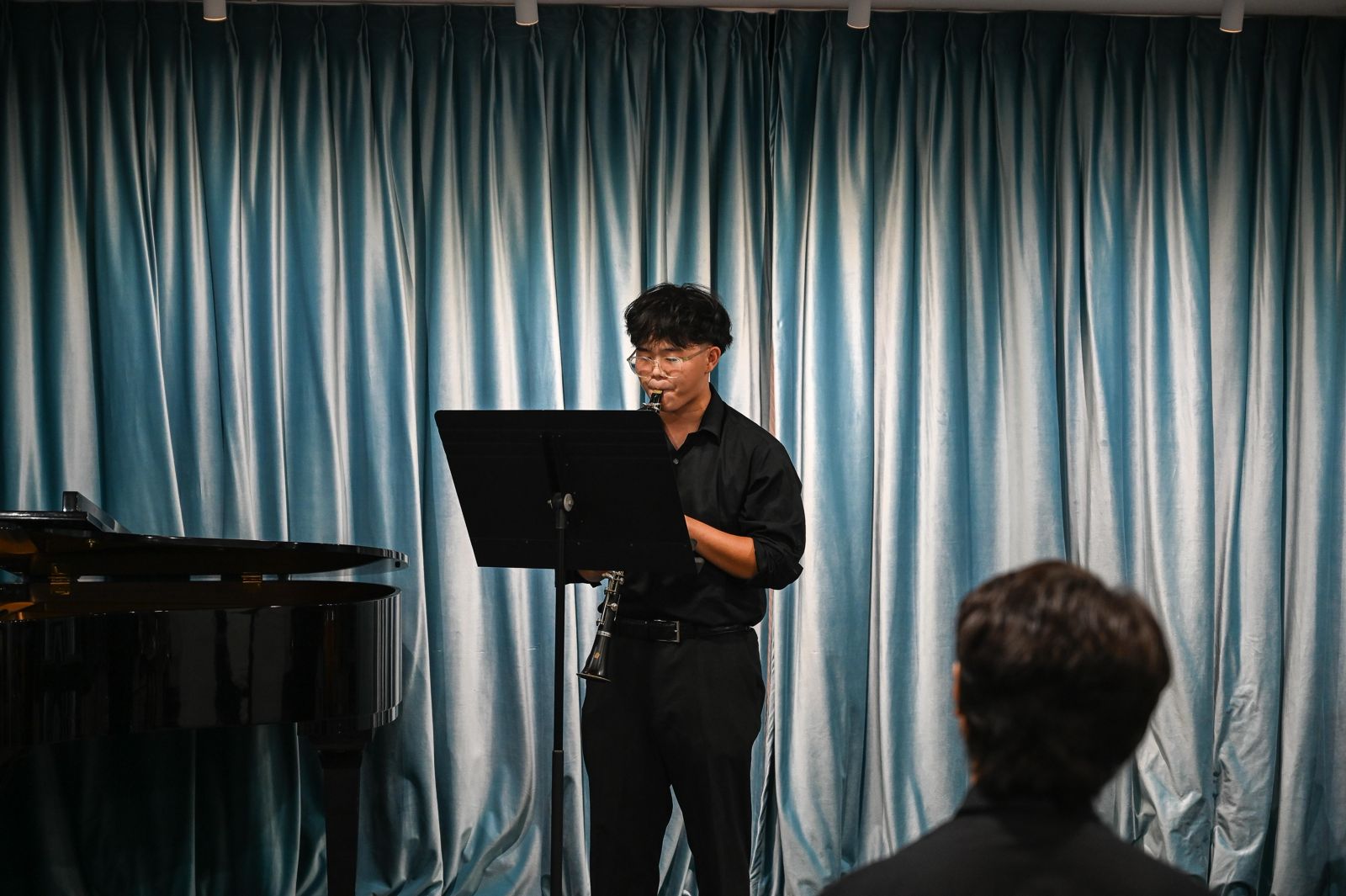 A student performing a clarinet solo to a listener at the BAS studio